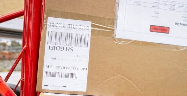 Close-up of shipping label attached to cardboard box representing Amazon FBA carrier label format