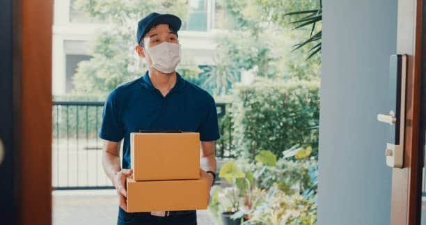 Close-up of courier handing a box to a customer in a door-to-door delivery.