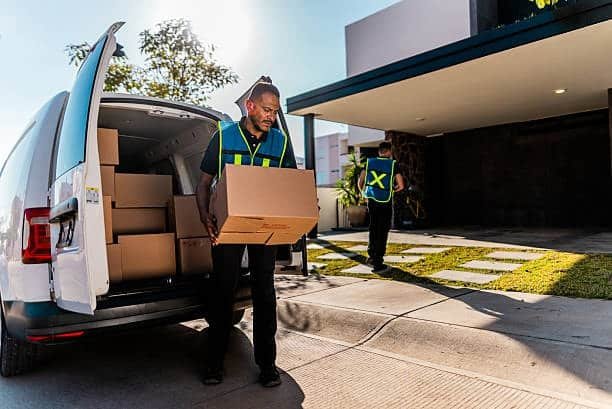 Courier handing over a labeled parcel during door-to-door shipping.