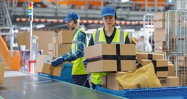 Employees on packing line preparing packages in e-commerce fulfillment center.