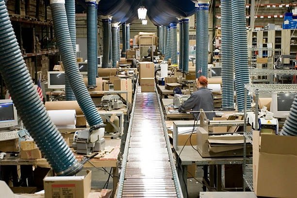 Assembly line in fulfillment center packing and preparing shipments for online orders.