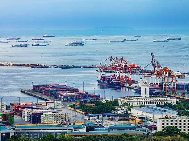 Large shipping port with cargo vessels and containers used for international and ground shipping.