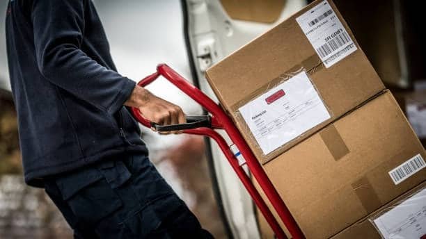“Worker moving cartons on hand truck representing handling fees in CFS charges”