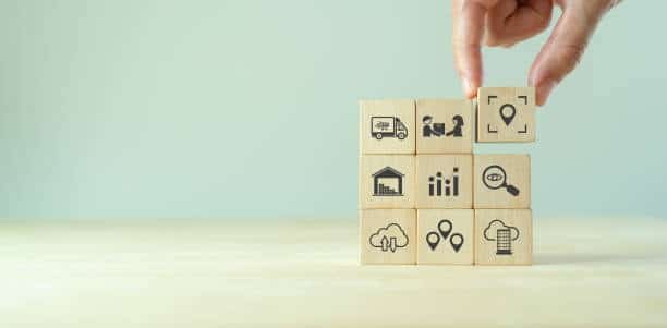 Wooden blocks with logistics and delivery icons representing e-commerce fulfillment planning.