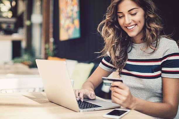 Smiling woman making an online purchase with laptop and credit card.