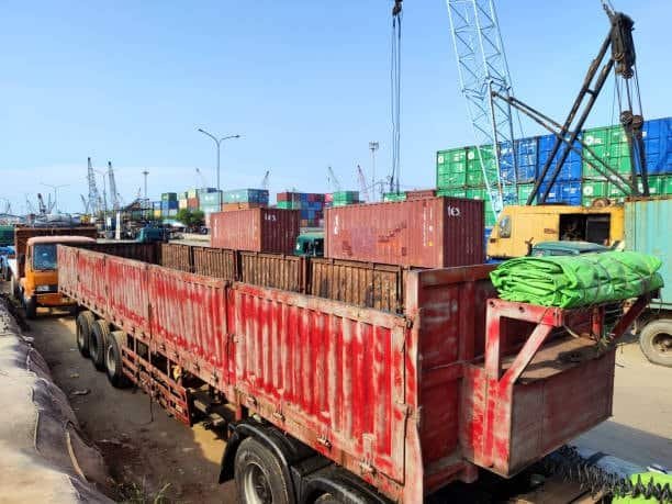“Red truck loaded with shipping containers showing FCL freight at container terminal”