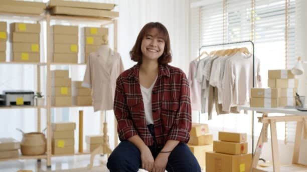 Entrepreneur in small warehouse surrounded by parcels for e-commerce fulfillment.