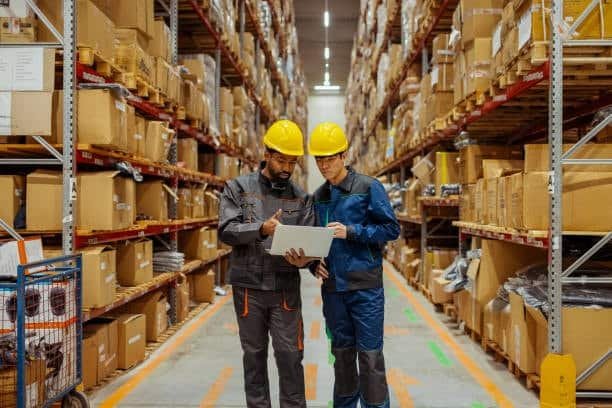 workers managing dropshipping inventory with laptop in warehouse