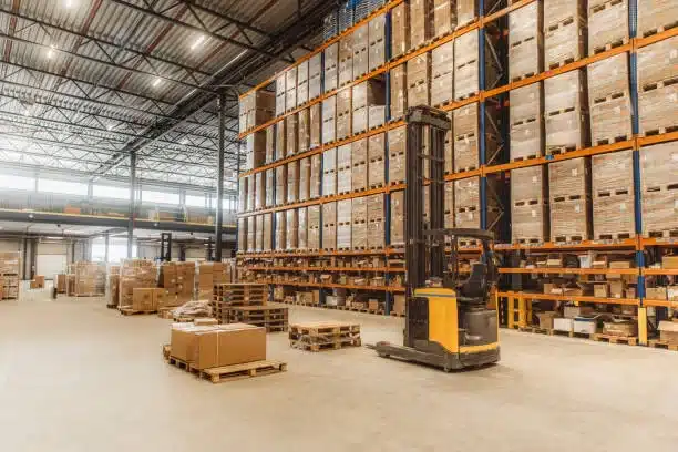 Distribution center warehouse with stacked pallets and forklift in operation.