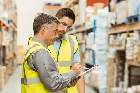 Warehouse worker in safety vest scanning Dell and Epson products stored after import customs duty clearance