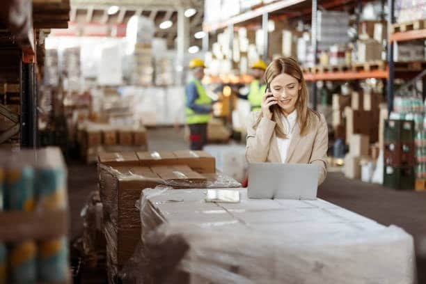 dropshipping manager on phone and laptop managing warehouse operations