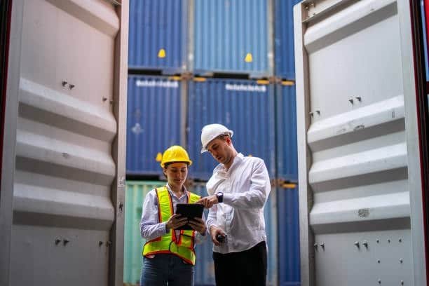 Logistics workers inspecting and recording cargo container details, important for LCL shipping documentation.