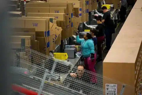 Workers organizing and processing packages in a Walmart Fulfillment Services warehouse.
