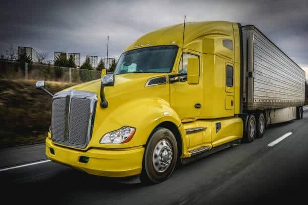 Large yellow freight truck delivering shipments for e-commerce fulfillment logistics.