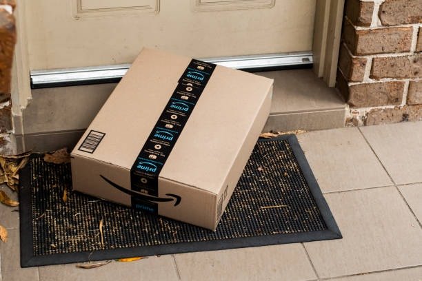 Person carrying Amazon Prime shipping box packaged according to Amazon’s requirements