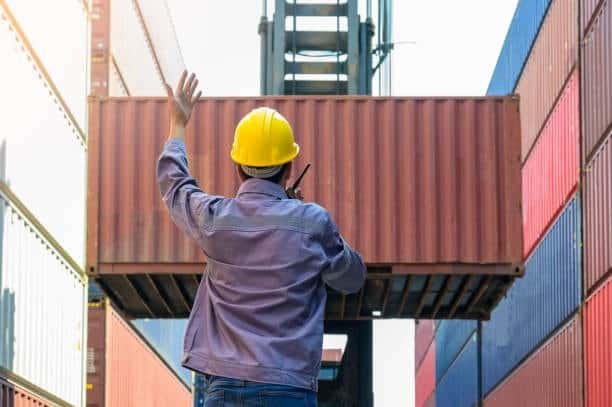 A CFS warehouse worker guiding a shipping container while it is being lifted for consolidation.