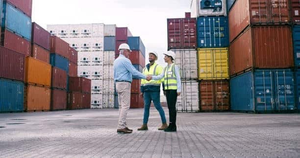 Shipping professionals meeting in a container yard to discuss CFS freight operations.