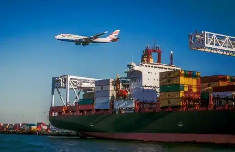 Cargo ship at port with airplane flying overhead, showing air and sea freight from China to Switzerland.