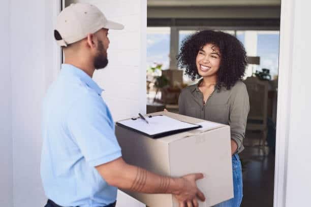 Customer smiling while receiving a delivery box from a door to door courier.
