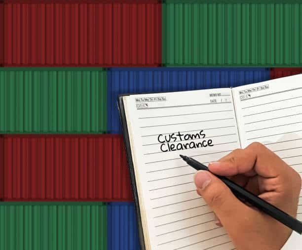 Person writing customs clearance notes in a logbook with containers in the background