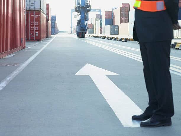 Customs security officer standing at port with directional arrow guiding cargo movement