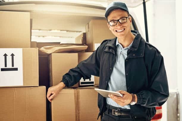 Courier standing beside a delivery van while managing door to door transport packages.