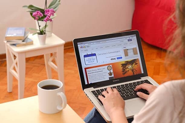 Woman using a laptop to manage eBay listings, illustrating how sellers adjust handling and shipping time settings.