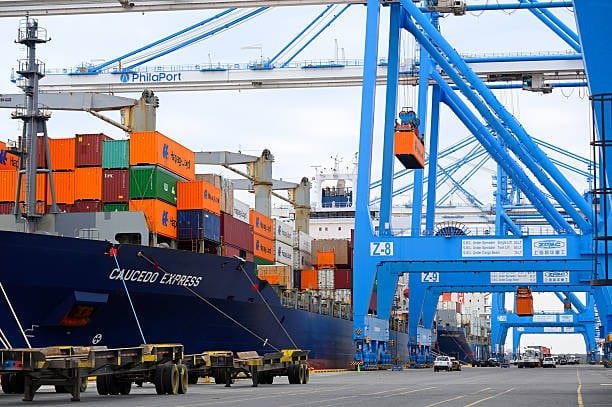 Port cranes loading containers for economy shipping outside the US.
