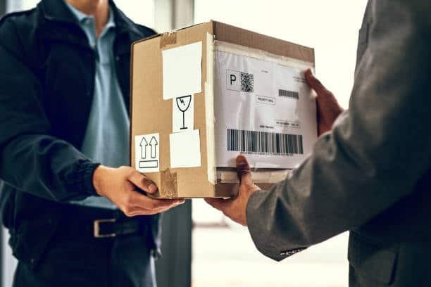 Courier handing over a labeled box during a door to door delivery service.