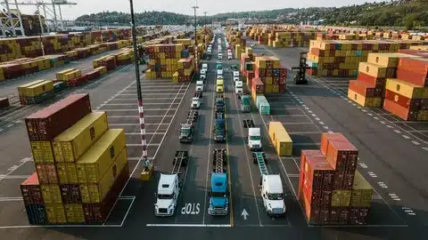 Aerial view of trucks lined up in a busy container terminal for ground shipping transport.