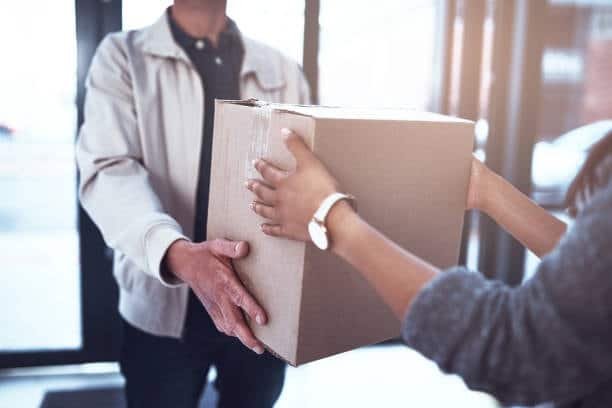Close-up of hands exchanging a delivery box during home delivery.