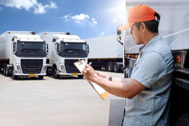 Logistics driver inspecting freight trucks before transportation, ensuring safe and efficient road freight logistics operations.