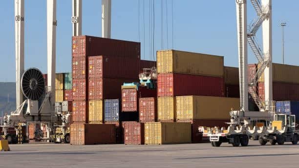 Port terminal with stacked containers and cranes supporting shipping channel logistics.