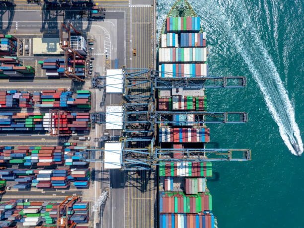Aerial shot of port operations with cranes loading a container ship, representing major international shipping channels.