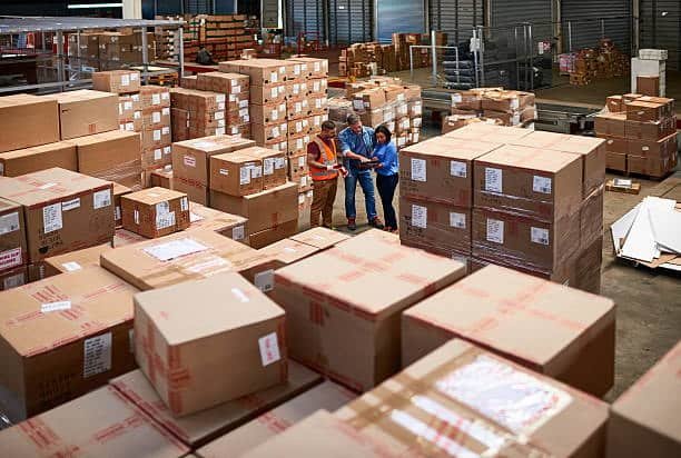 Warehouse staff reviewing and inspecting large shipping boxes before dispatch.