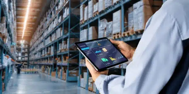 Warehouse employee tracking logistics data on tablet inside storage facility
