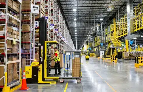Worker operating forklift in warehouse section of fulfillment center.