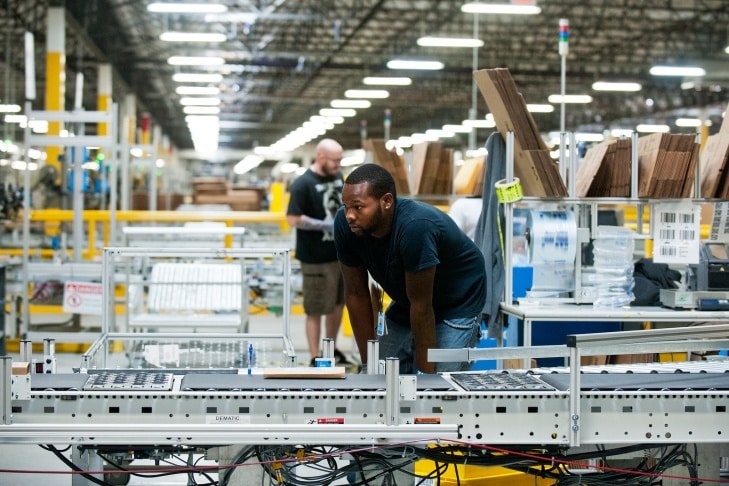 Warehouse workers preparing and packing apparel items on an automated conveyor line.