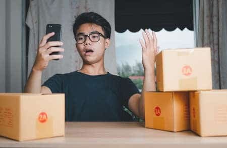 Customer reviewing AliExpress order issues with packages on table.