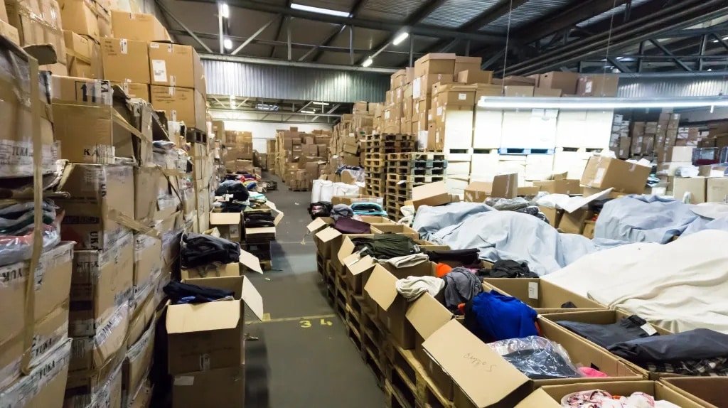 Disorganized apparel warehouse with open boxes and mixed inventory, highlighting the need for professional 3PL management.