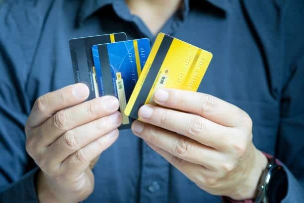Person holding multiple credit cards highlighting online payment choices.
