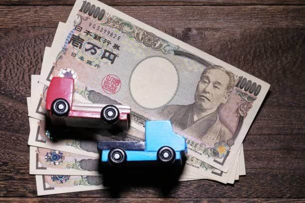 Toy import cost concept showing wooden toy cars on Japanese yen notes representing trade and currency exchange in global toy imports.