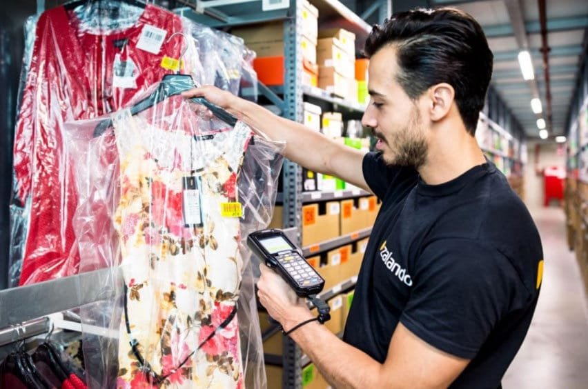 Warehouse employee scanning a dress with a barcode scanner to track inventory in apparel fulfillment.