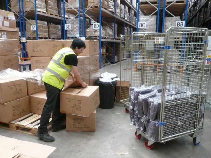 Warehouse employee lifting apparel shipment boxes in a 3PL fulfillment center.