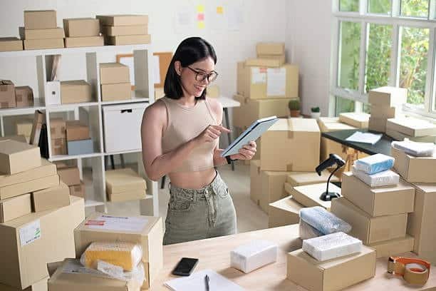 Woman managing online store orders with packages representing AliExpress shopping.