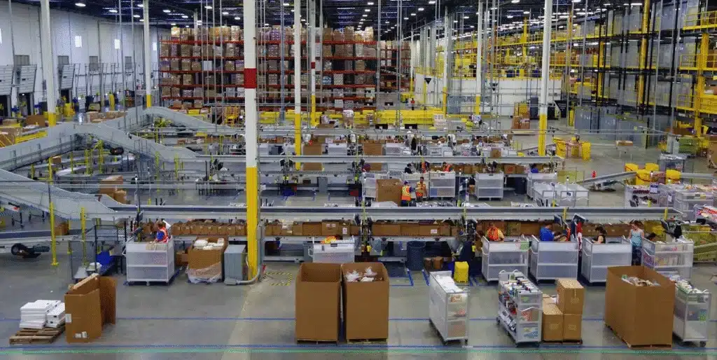 Amazon FBA fulfillment center showing processing lines, inventory stations, and warehouse storage.