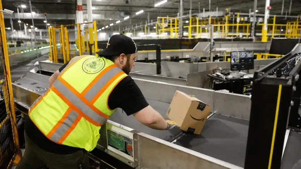 Amazon warehouse employee placing a package on a conveyor belt during FBA prep and processing, showing how operational steps affect overall FBA prep costs.