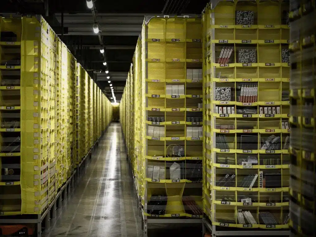 Rows of yellow Amazon FBA storage bins containing products in a fulfillment center.