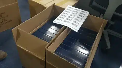 Open cartons filled with products and FNSKU barcode labels being applied for Amazon FBA compliance.