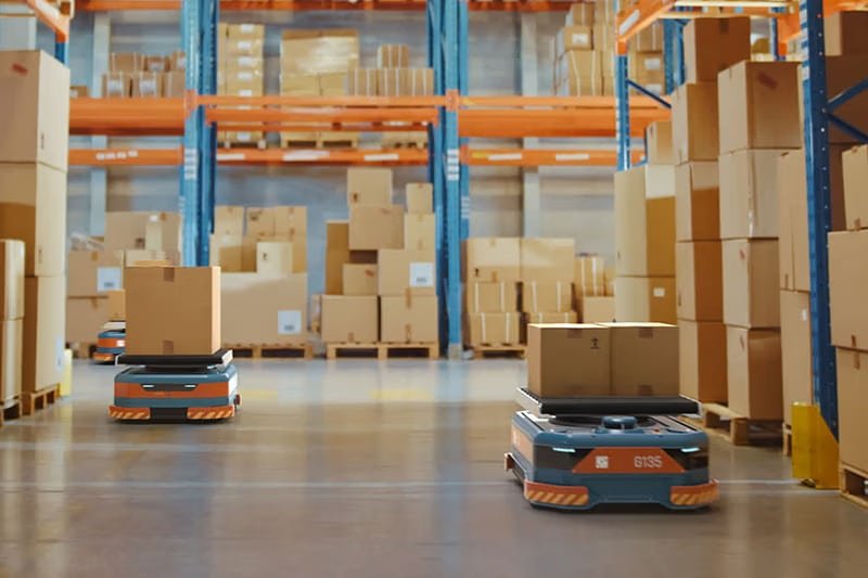 Autonomous AGV robots transporting packages inside a modern warehouse, showcasing automation in B2B fulfillment and efficient eCommerce logistics.